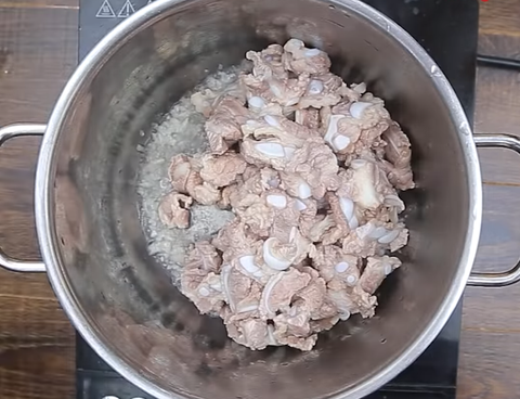 Đun sôi hành băm với dầu ăn, cho sườn sụn vào nồi